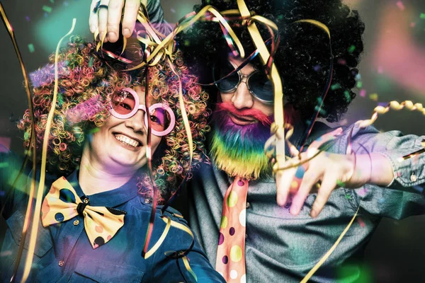 Happy man and woman wearing color wigs with party items