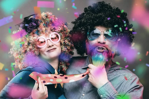 Happy man and woman wearing color wigs with party items