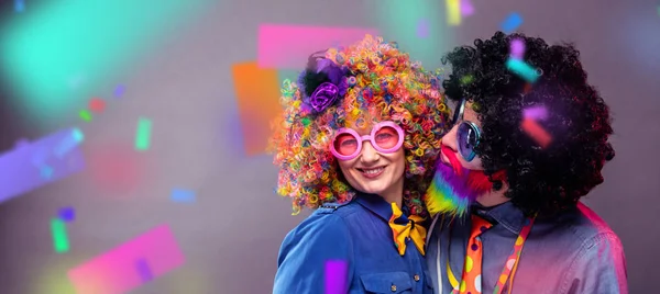 Happy man and woman wearing color wigs with party items