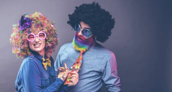 Happy man and woman wearing color wigs with party items