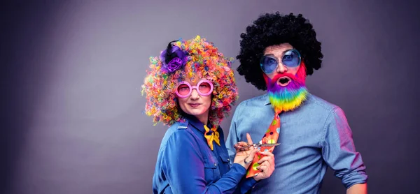 Happy man and woman wearing color wigs with party items