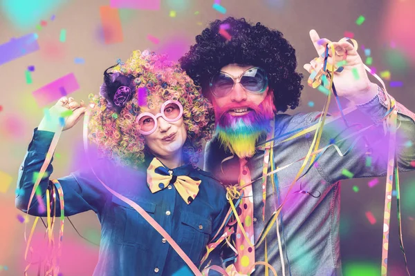Happy man and woman wearing color wigs with party items