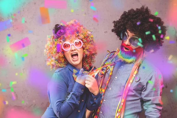 Happy man and woman wearing color wigs with party items