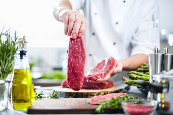 Chef in restaurant kitchen cooking,he is cutting meat or steak 