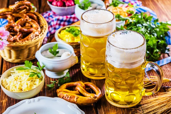 Oktoberfest beer, pretzels and various Bavarian specialties on wooden background