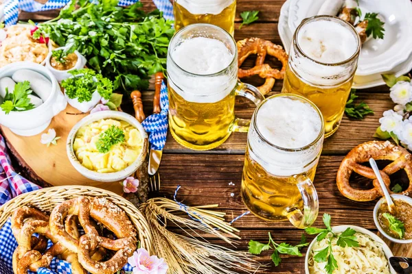 Oktoberfest beer, pretzels and various Bavarian specialties on wooden background