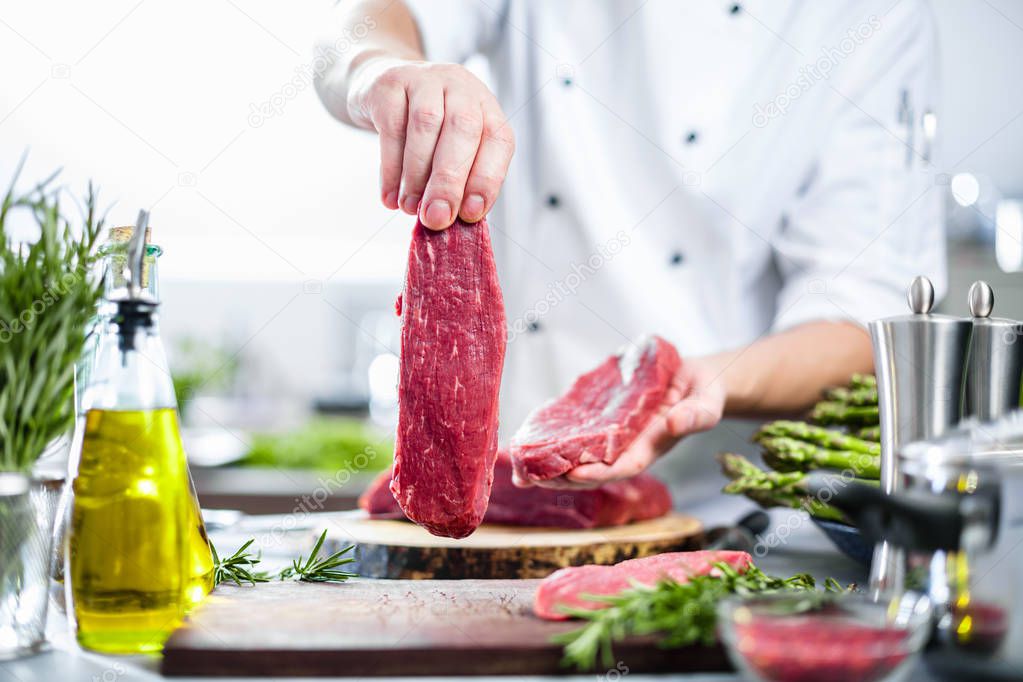 Chef in restaurant kitchen cooking,he is cutting meat or steak 