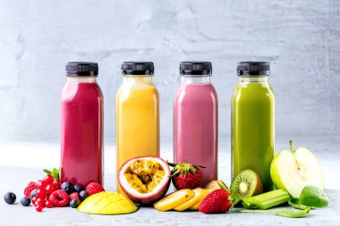 Düz-lay şişelerde taze tropikal meyve ve beton zemin üzerine superfoods ile renkli smoothies
