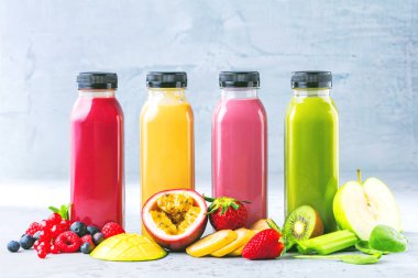 Düz-lay şişelerde taze tropikal meyve ve beton zemin üzerine superfoods ile renkli smoothies
