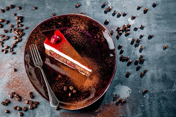 Черная тарелка с вкусным шоколадным тортом на сером фоне

