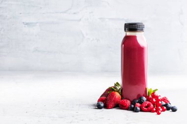 Düz-lay şişelerde taze tropikal meyve ve beton zemin üzerine superfoods ile renkli smoothies
