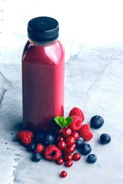 Düz-lay şişelerde taze tropikal meyve ve beton zemin üzerine superfoods ile renkli smoothies