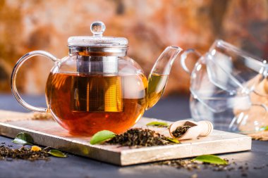 Taze demlendi siyah çay, sıcak yumuşak ışık, koyu arka plan.