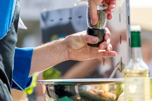 Closeup mid section of a chef putting salt and Pepper in the kitchen