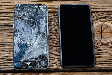 ahşap arka plan üzerinde kırık dokunmatik ekrana sahip cep telefonu.