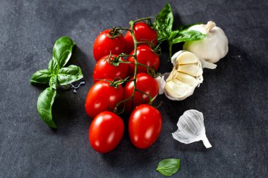 Taze domates fesleğen sarımsak ve deniz ile siyah arduvaz arka plan üzerine tuz.