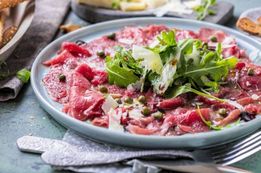 Dana carpaccio hardal ve parmesan ile siyah plaka üzerinde