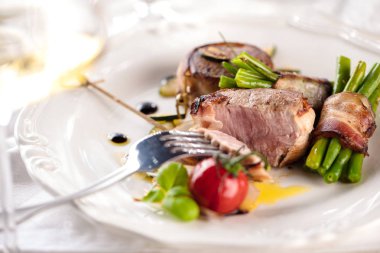 Pastırma tablo üzerinde sarılı sulu domuz madalyonlar