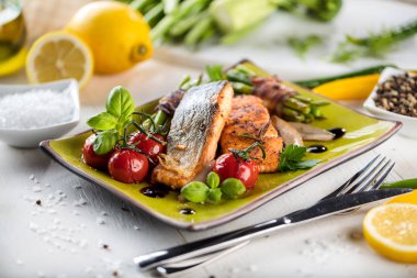 Ahşap masa üzerinde yeşil taş tabakta servis sebzeli ızgara somon 