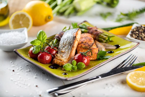 Ahşap masa üzerinde yeşil taş tabakta servis sebzeli ızgara somon 