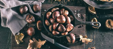 Eski ahşap masa üzerinde özel delikli tavada kavrulmuş kestane