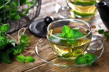 Bir fincan sıcak çay, kamış şekeri, çay yaprakları ve nane bitkisi..