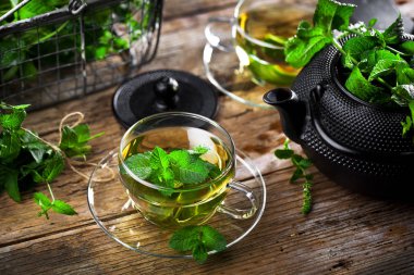 Bir fincan sıcak çay, kamış şekeri, çay yaprakları ve nane bitkisi..