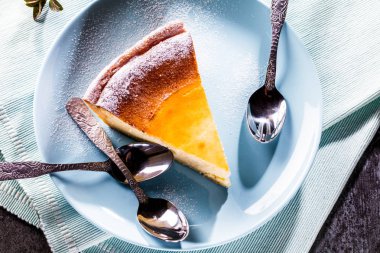 Mavi ahşap masa üzerinde lezzetli ev yapımı peynirli kek. Seçici odak