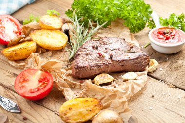 Lezzetli, ızgara sığır eti biftek ile kızarmış patates ve taze yeşil ot salatası havai görünümü eski ahşap masa