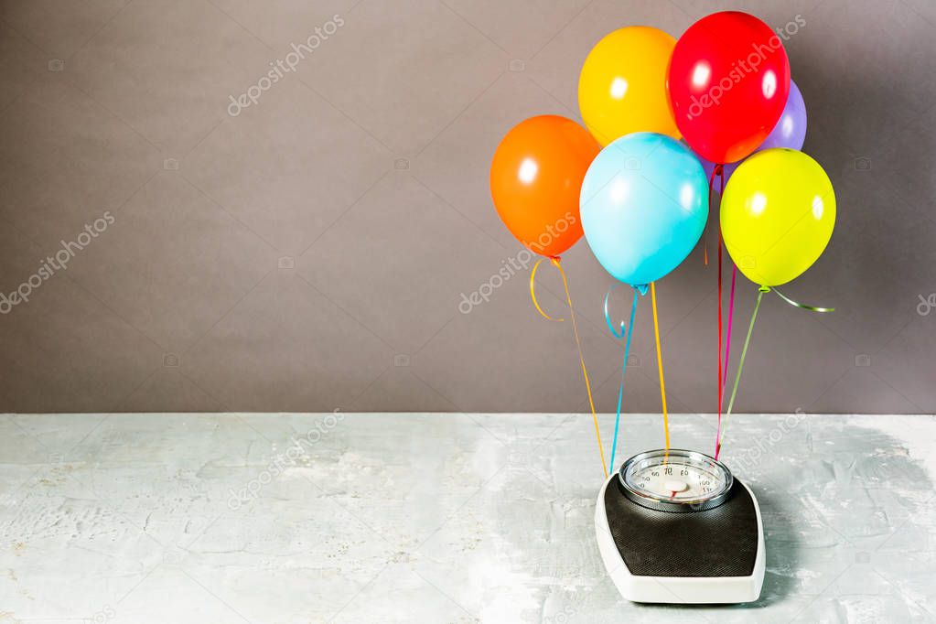 Bathroom scales with colorful balloons. Slimming concept