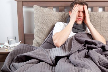 Man feeling bad lying in the bed and coughing clipart