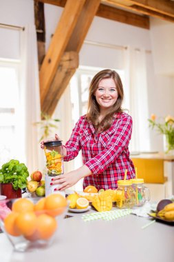 Genç gülümseyen kadın evde mutfak blender Smoothie taze yeşillikleri ile yapma.