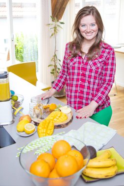 Genç gülümseyen kadın evde mutfak blender Smoothie taze yeşillikleri ile yapma.