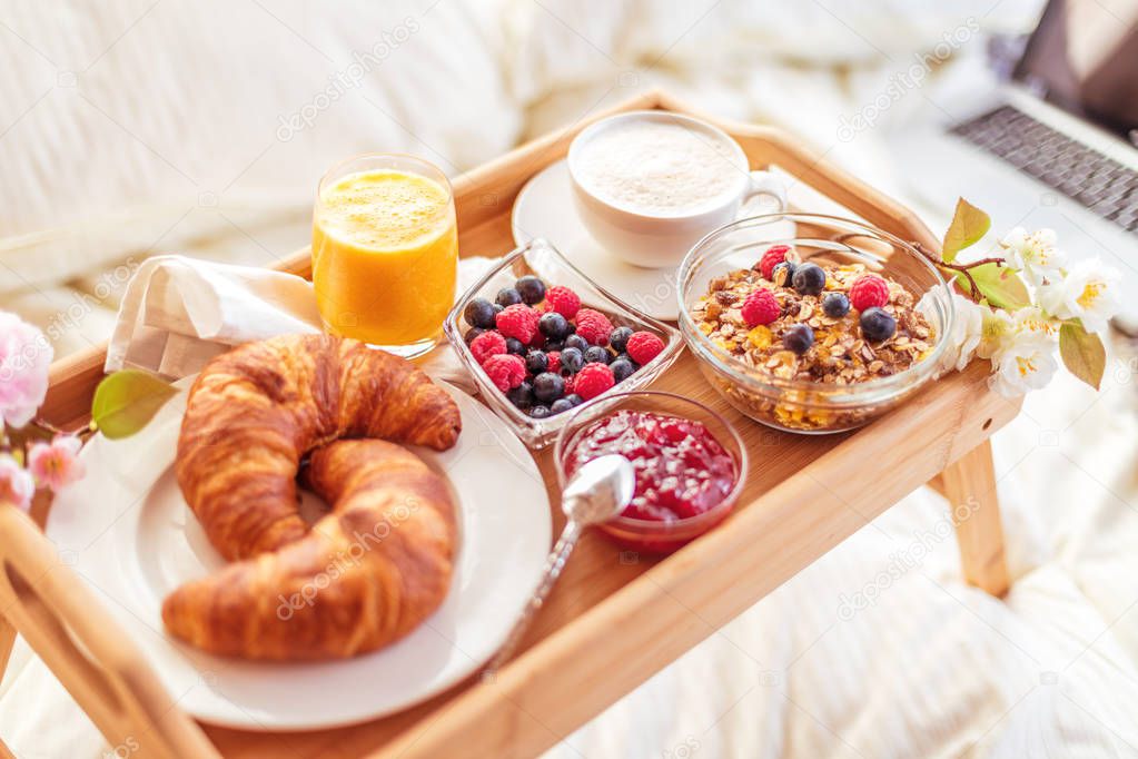 breakfast in bed with fruits and pastries on a tray