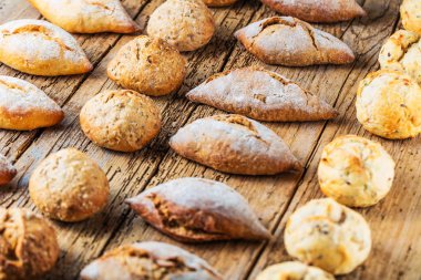 Ahşap masa üzerinde taze ekmek çeşitleri. İzole kahverengi zemin üzerine ekmek çeşitliliği.