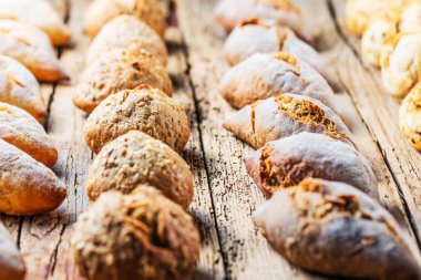 Ahşap masa üzerinde taze ekmek çeşitleri. İzole kahverengi zemin üzerine ekmek çeşitliliği.