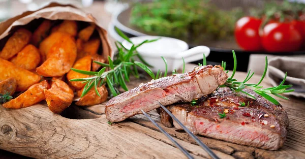 Siyah taştan arka planda patates ve orta pişmiş biftek. Üst manzara, düz uzanma