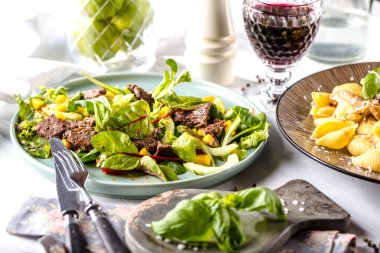 Koyu ahşap zemin üzerine karışık yeşillik (roka, mesclun, mache) ile taze salata tabağı kapatın. Manzo