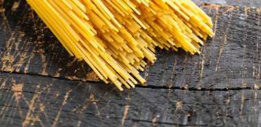 Rustik bir arka plan üzerinde sarı uzun spagetti. Sarı İtalyan makarna. Uzun spagetti.