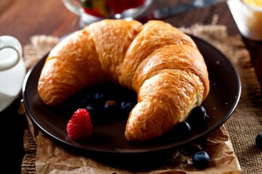 Lezzetli kahvaltı taze kruvasanlar ve eski ahşap zemin üzerine olgun çilek ile,