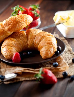 Lezzetli kahvaltı taze kruvasanlar ve eski ahşap zemin üzerine olgun çilek ile,