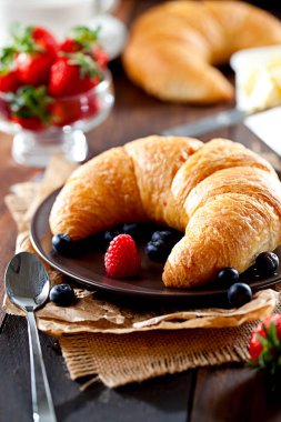 Lezzetli kahvaltı taze kruvasanlar ve eski ahşap zemin üzerine olgun çilek ile,