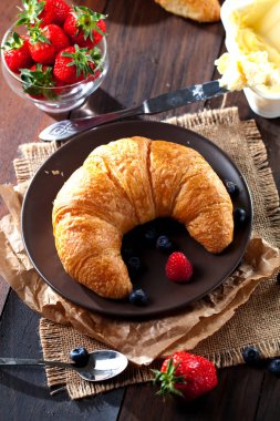 Lezzetli kahvaltı taze kruvasanlar ve eski ahşap zemin üzerine olgun çilek ile,