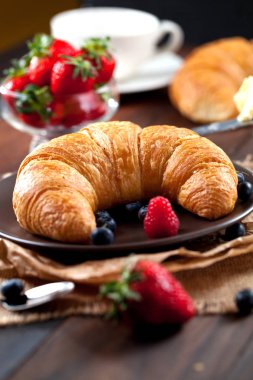 Lezzetli kahvaltı taze kruvasanlar ve eski ahşap zemin üzerine olgun çilek ile,