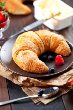 Lezzetli kahvaltı taze kruvasanlar ve eski ahşap zemin üzerine olgun çilek ile,