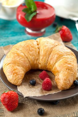 Lezzetli kahvaltı taze kruvasanlar ve eski ahşap zemin üzerine olgun çilek ile,