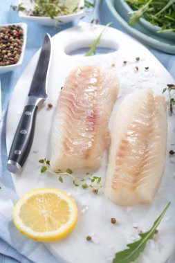 Taze balık, otlar ve limon eklenmesi ile ham morina fileto 