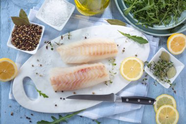 Taze balık, otlar ve limon eklenmesi ile ham morina fileto 