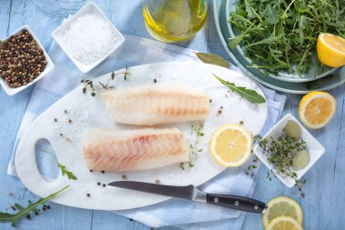 Taze balık, otlar ve limon eklenmesi ile ham morina fileto 