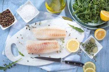 Fresh fish, raw cod fillets with addition of herbs and lemon  clipart